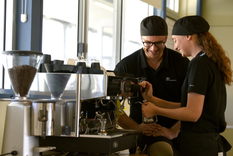 A teacher teaching a student to make coffee